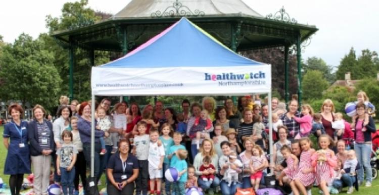 a group picture of all the attendees of the breastfeeding picnic under a Healthwatch gazebo