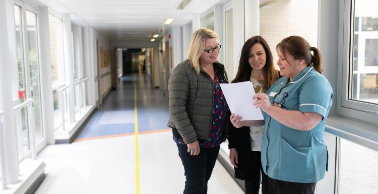 Three women talking in hospital corridor
