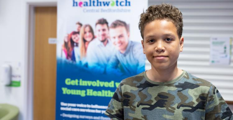 Young person in front of Healthwatch banner smiling 