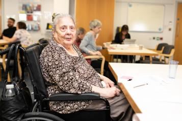 Older women wheelchair user at table with pen