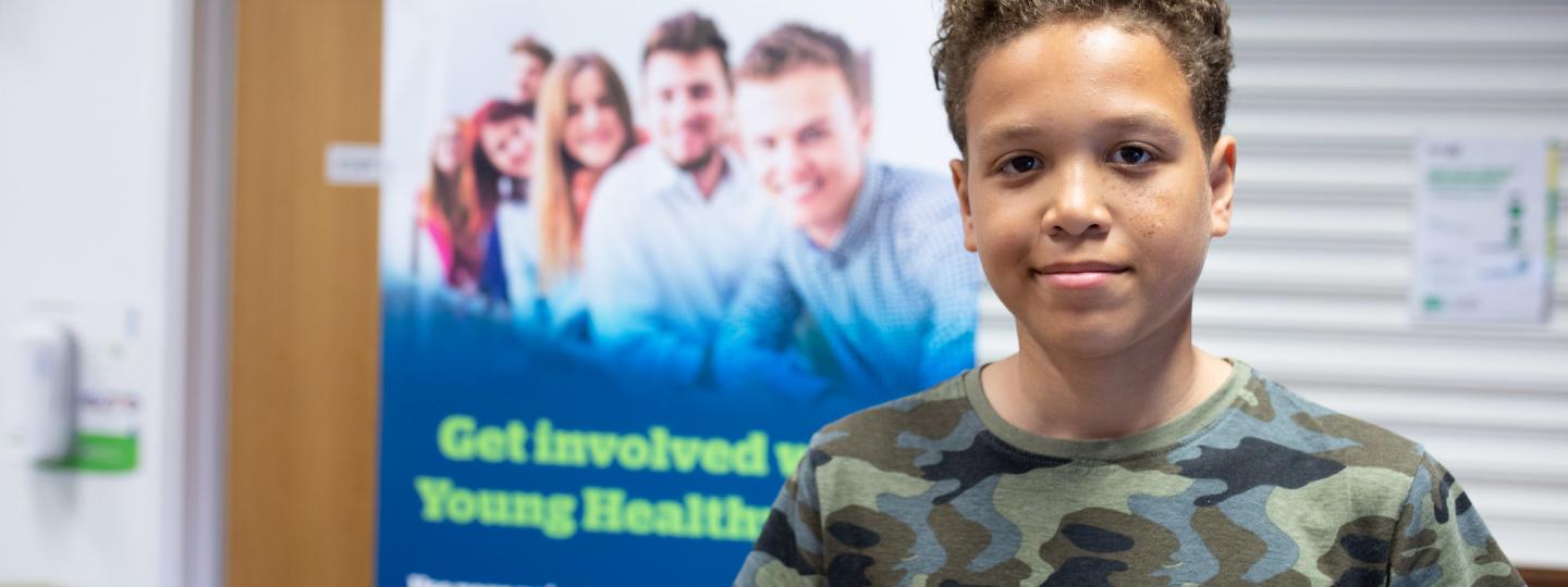 Young person in front of Healthwatch banner smiling 