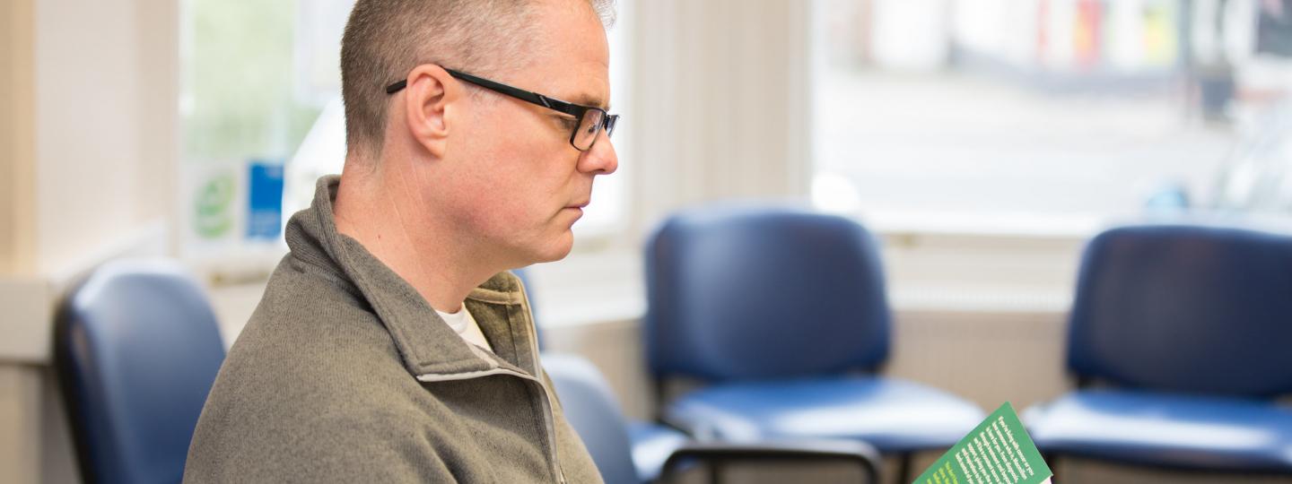 Man reading leaflet in waiting room